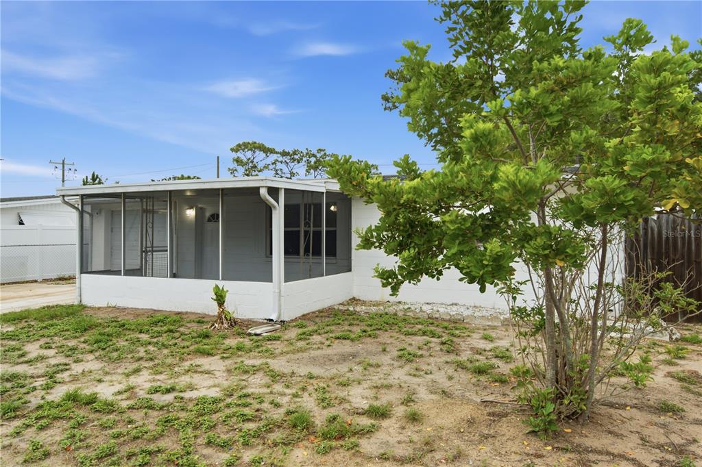 A white house with a screened-in porch and a large tree in the front yard — 2122 HOLIDAY DRIVE, HOLIDAY, FL