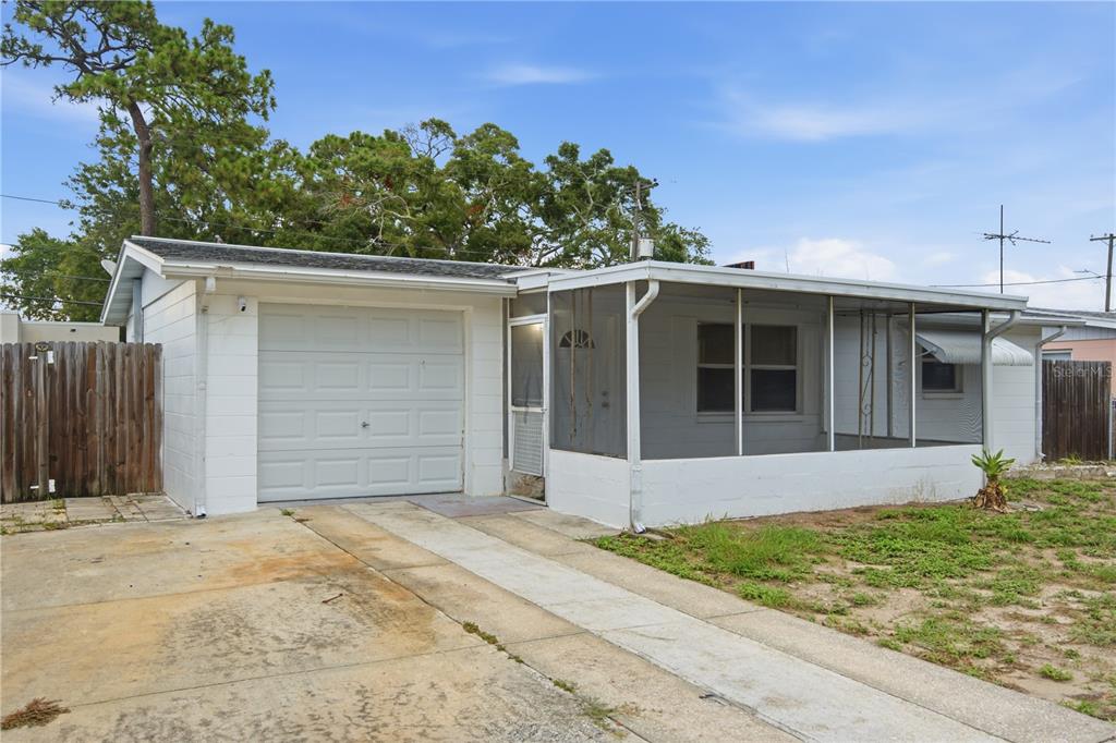 A white single-story house with a garage, a screened-in front porch, and a concrete driveway — 2122 HOLIDAY DRIVE, HOLIDAY, FL