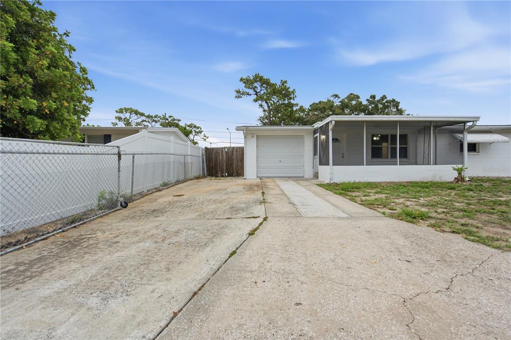 A concrete driveway leads to a single-car garage and a screened-in porch of a house — 2122 HOLIDAY DRIVE, HOLIDAY, FL