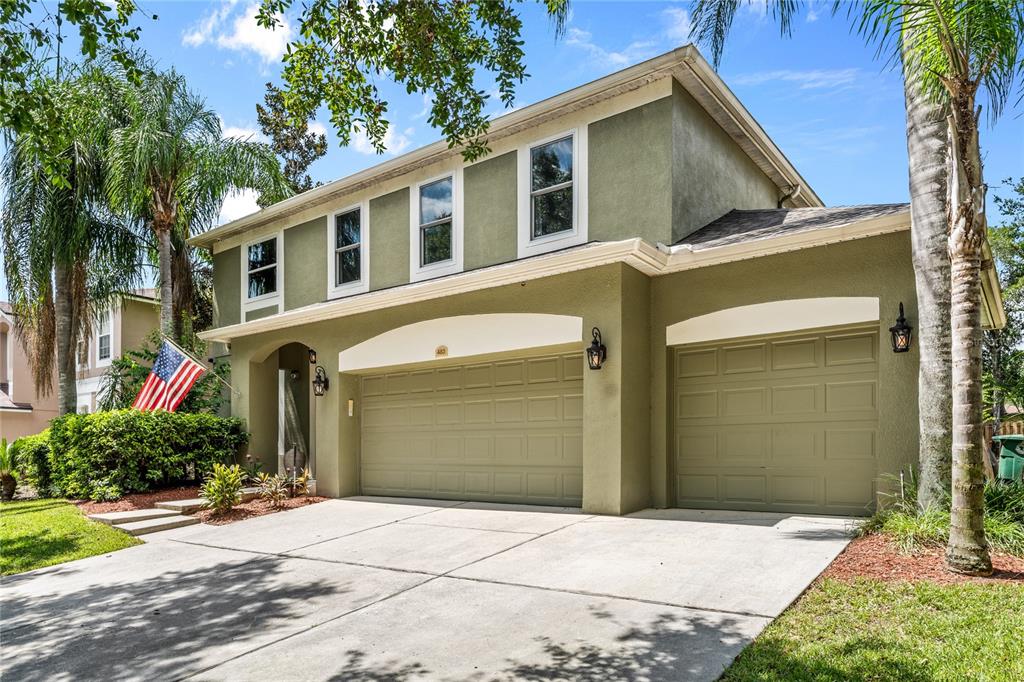 A two-story house with a three-car garage, olive green stucco siding, and palm trees — 483 VIA TUSCANY LOOP, LAKE MARY, FL