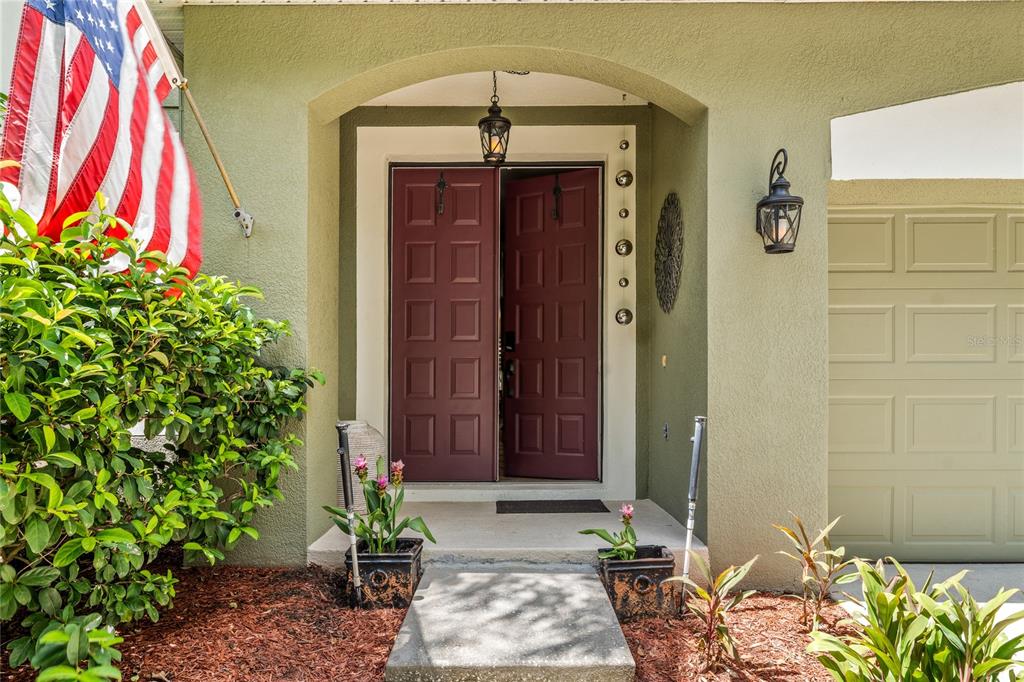 The exterior view shows a front entrance with double maroon doors and an American flag — 483 VIA TUSCANY LOOP, LAKE MARY, FL
