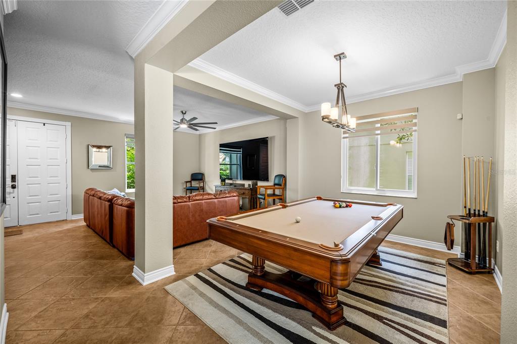 A game room features a pool table on a striped rug and an adjacent living area — 483 VIA TUSCANY LOOP, LAKE MARY, FL