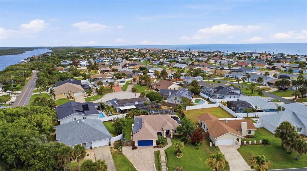 A screened-in swimming pool with a concrete deck and lush landscaping in the background — 3 SEABRIDGE DRIVE, ORMOND BEACH, FL