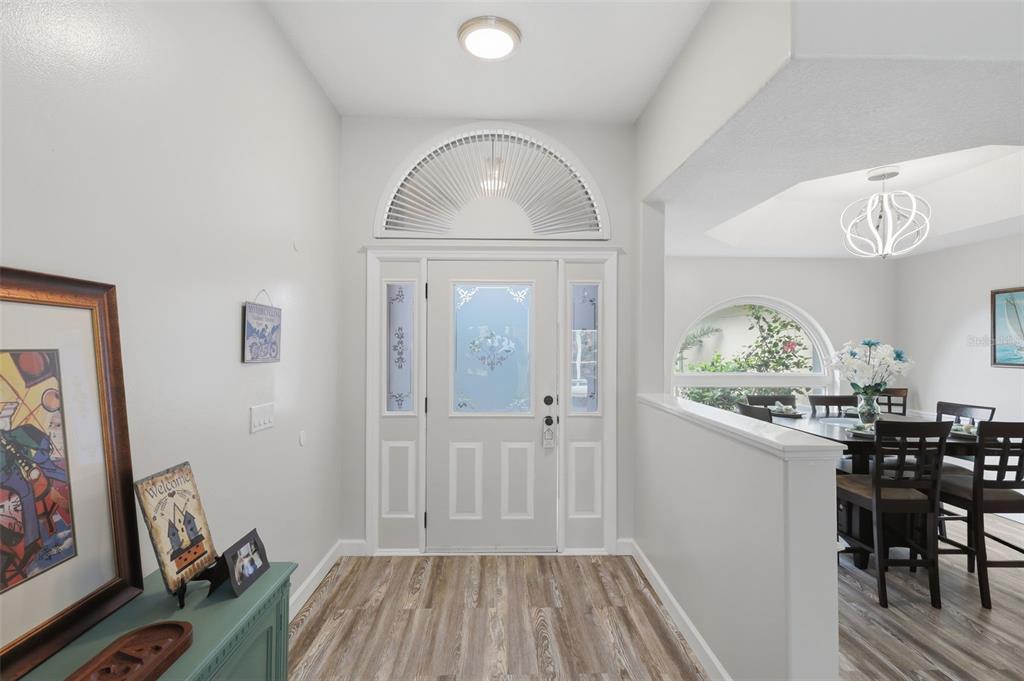 An entryway with wood-look flooring leads to a front door with a decorative arched transom — 3 SEABRIDGE DRIVE, ORMOND BEACH, FL