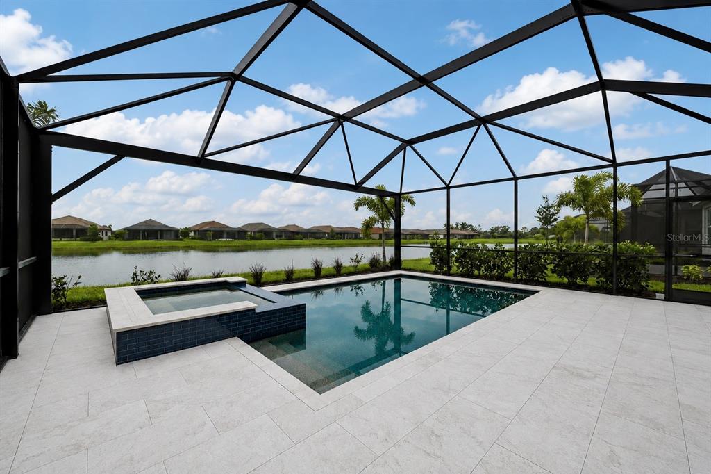 A screened-in pool and spa overlook a lake behind a residential neighborhood — 3362 ALBA CIRCLE, BRADENTON, FL