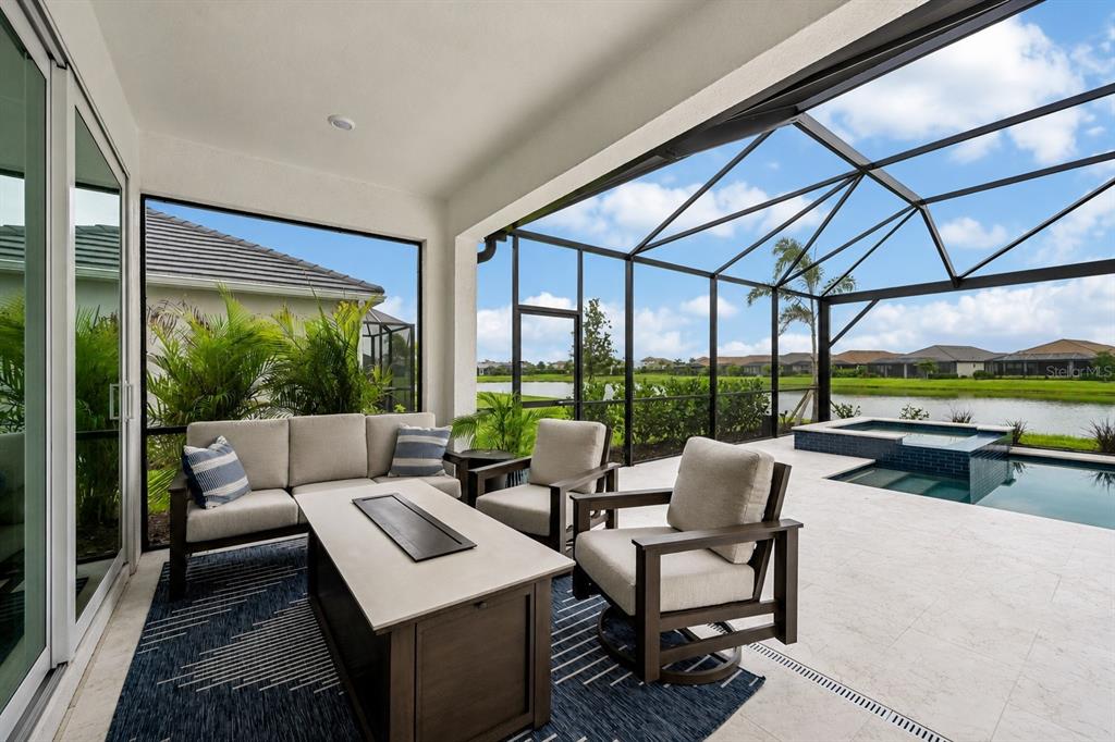 A covered patio features outdoor furniture, a fire pit, and a screened-in pool area — 3362 ALBA CIRCLE, BRADENTON, FL