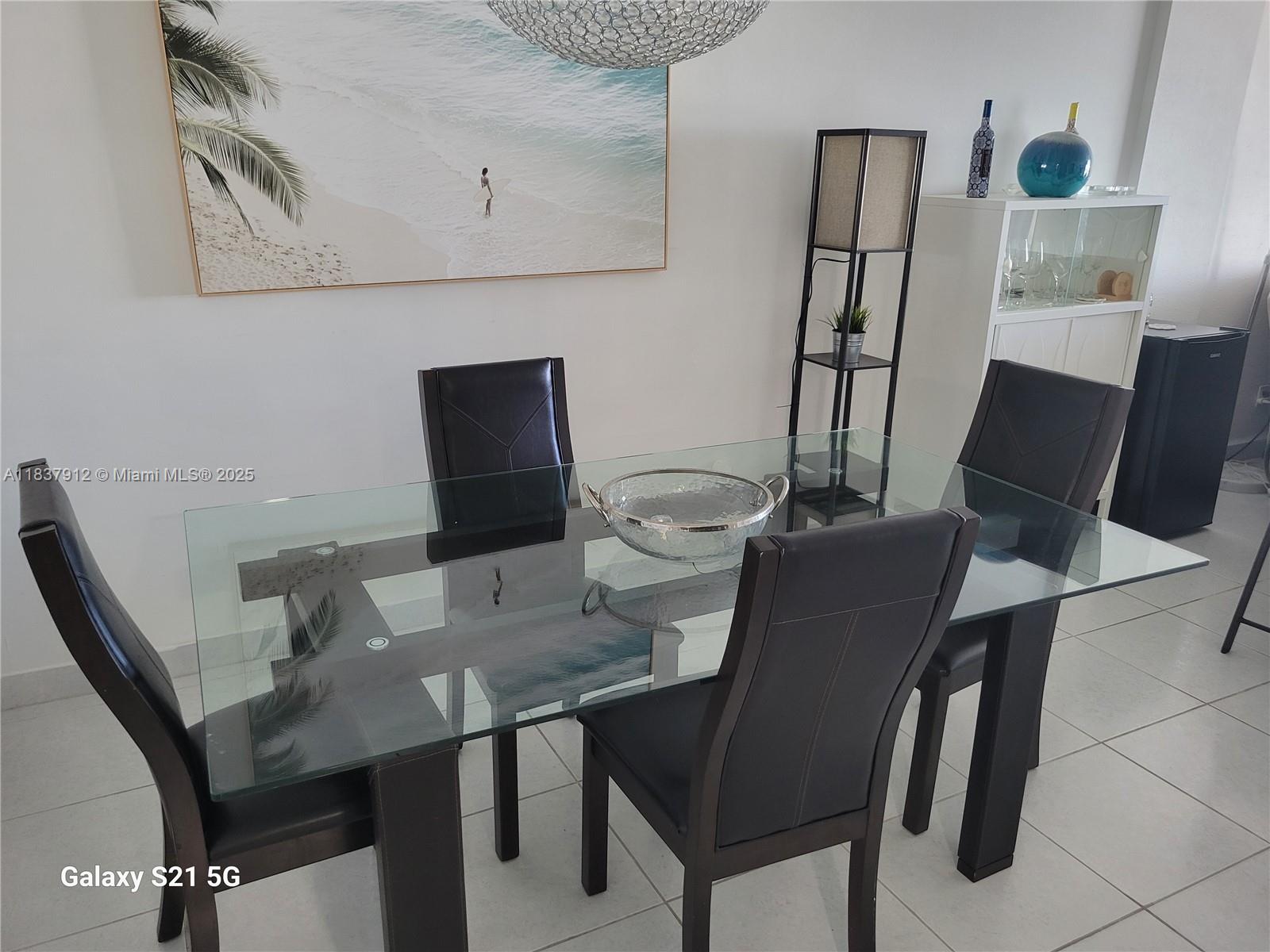 A dining room features a glass-topped table, four dark chairs, and a large beach print — 1849 S Ocean Dr # 1407, Hallandale Beach FL 33009, HALLANDALE BEACH, FL