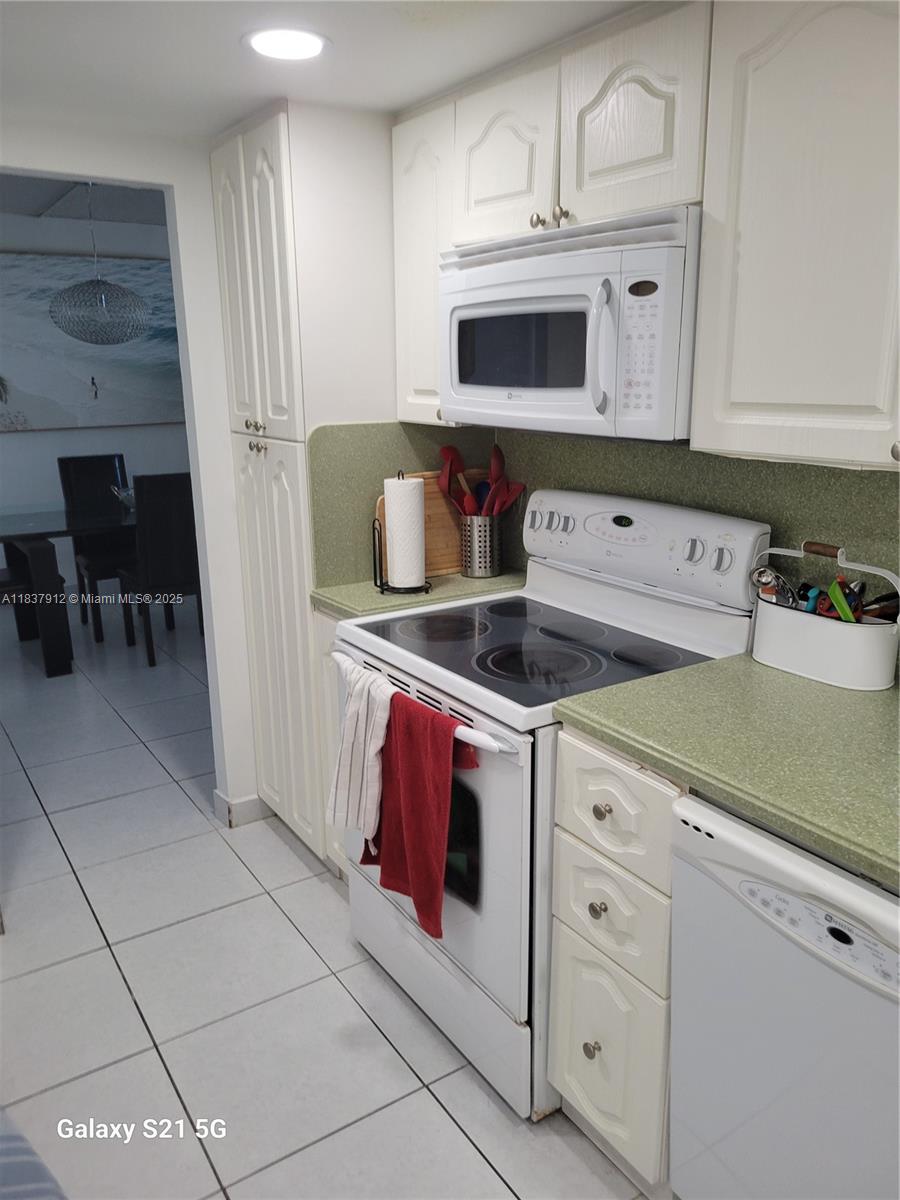 A kitchen features white cabinetry, a white electric range, and green countertops — 1849 S Ocean Dr # 1407, Hallandale Beach FL 33009, HALLANDALE BEACH, FL