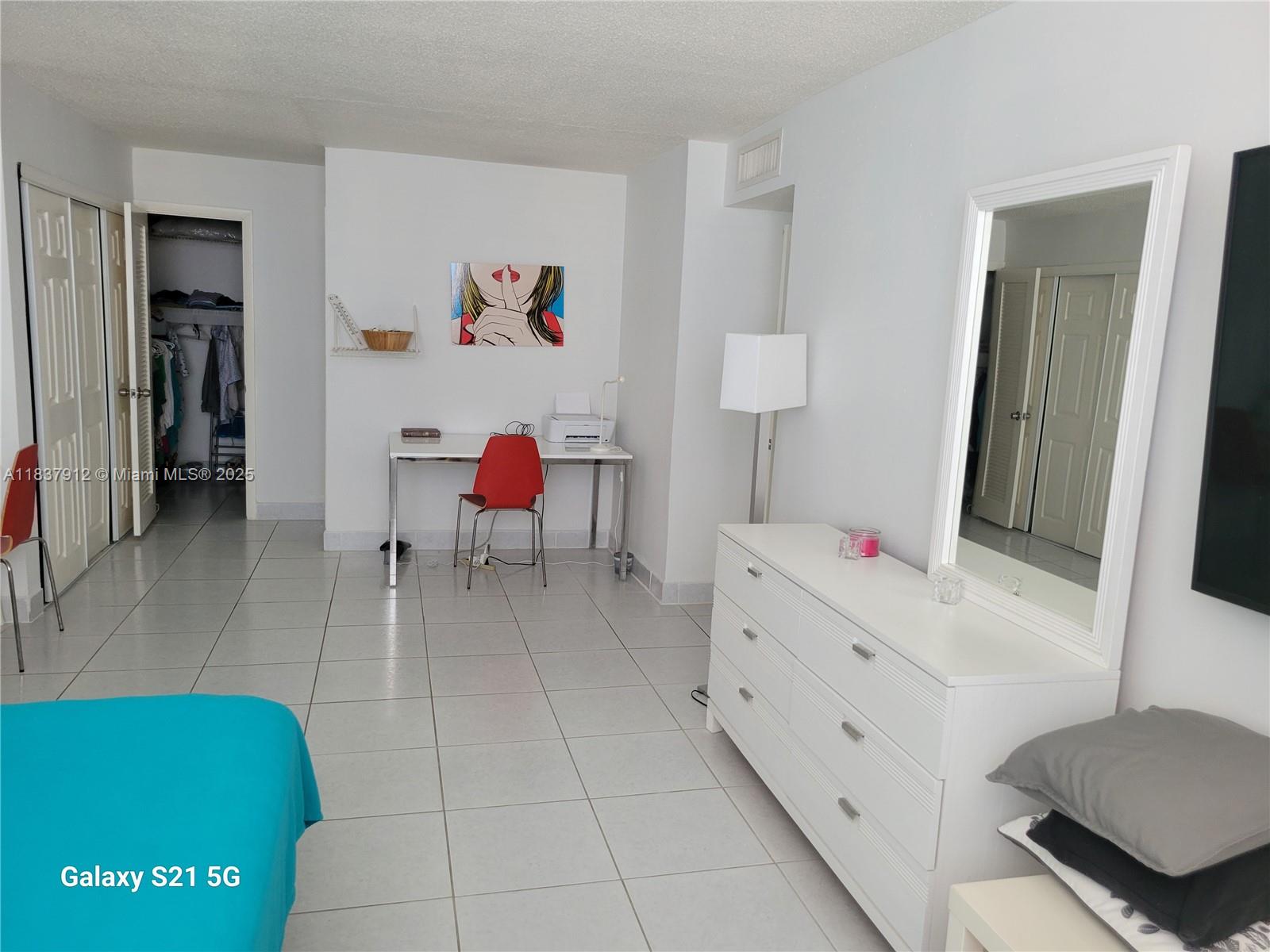 A bedroom with white tile floors, a white dresser, a desk, and a closet — 1849 S Ocean Dr # 1407, Hallandale Beach FL 33009, HALLANDALE BEACH, FL