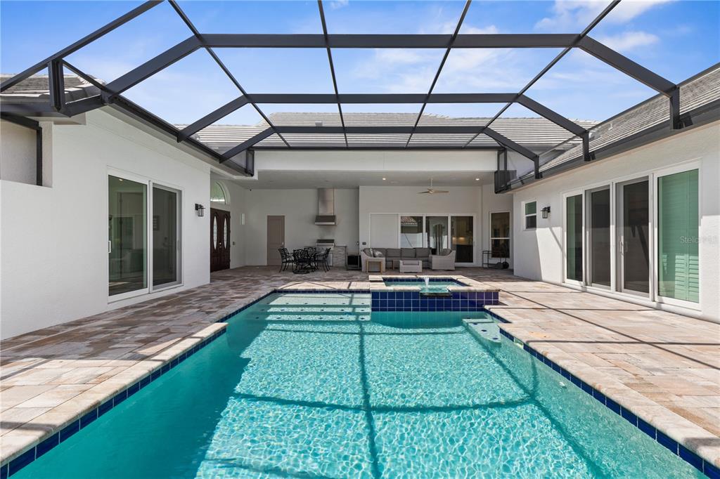A screened-in patio features a swimming pool with an attached spa and outdoor seating area — 114 NEW LEATHERWOOD DRIVE, PALM COAST, FL
