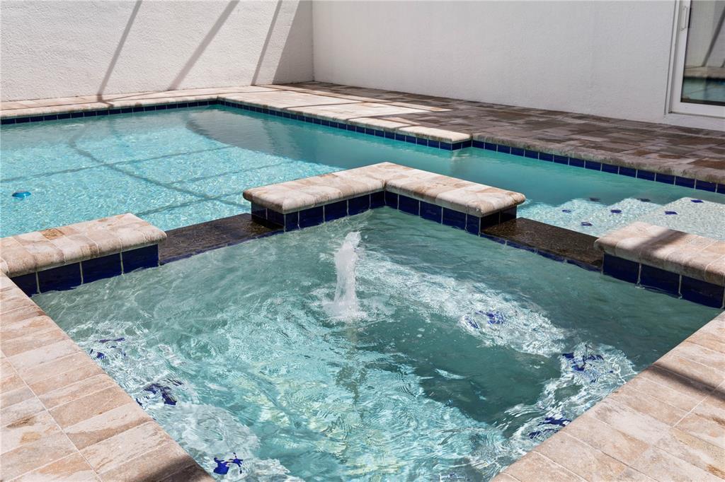 A square spa with a central fountain sits adjacent to a rectangular swimming pool — 114 NEW LEATHERWOOD DRIVE, PALM COAST, FL