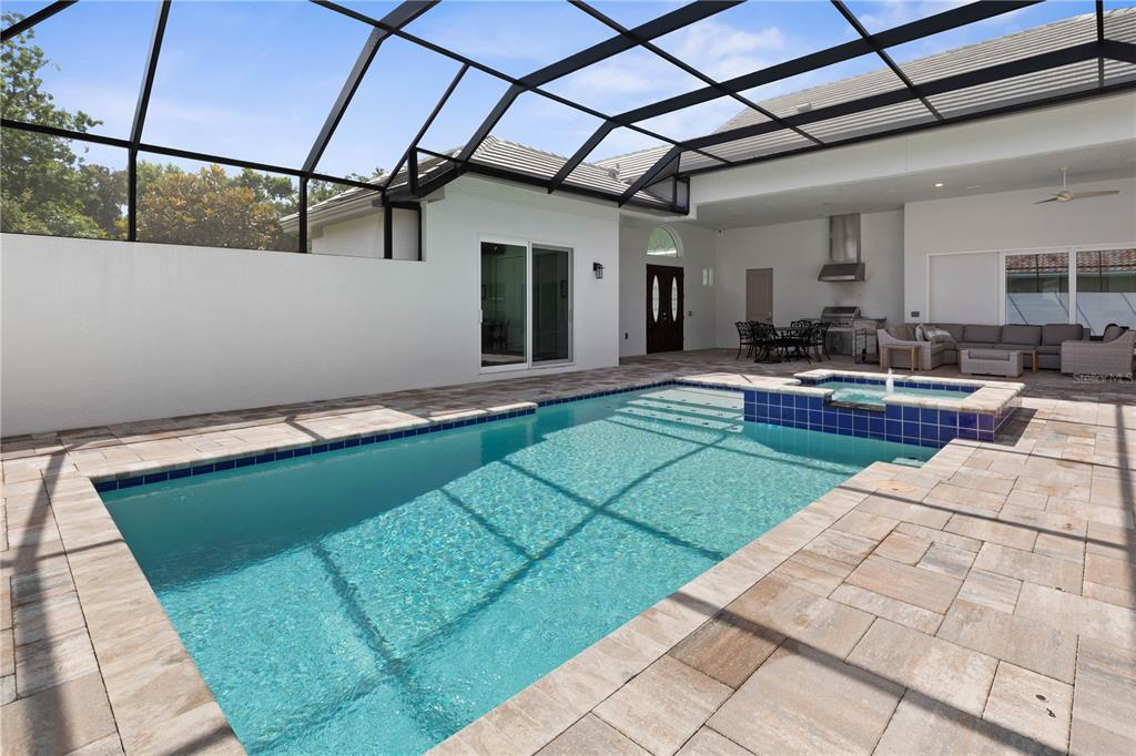 A screened-in patio features a swimming pool, a raised spa, and an outdoor kitchen area — 114 NEW LEATHERWOOD DRIVE, PALM COAST, FL