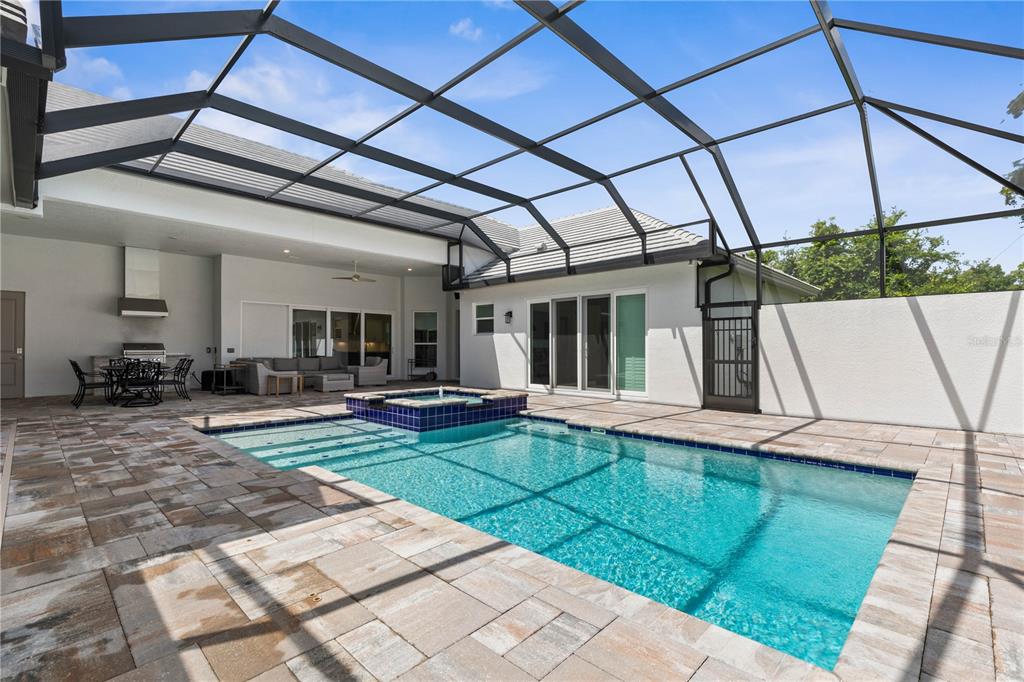 A screened-in patio features a swimming pool with a raised spa and stone paver decking — 114 NEW LEATHERWOOD DRIVE, PALM COAST, FL