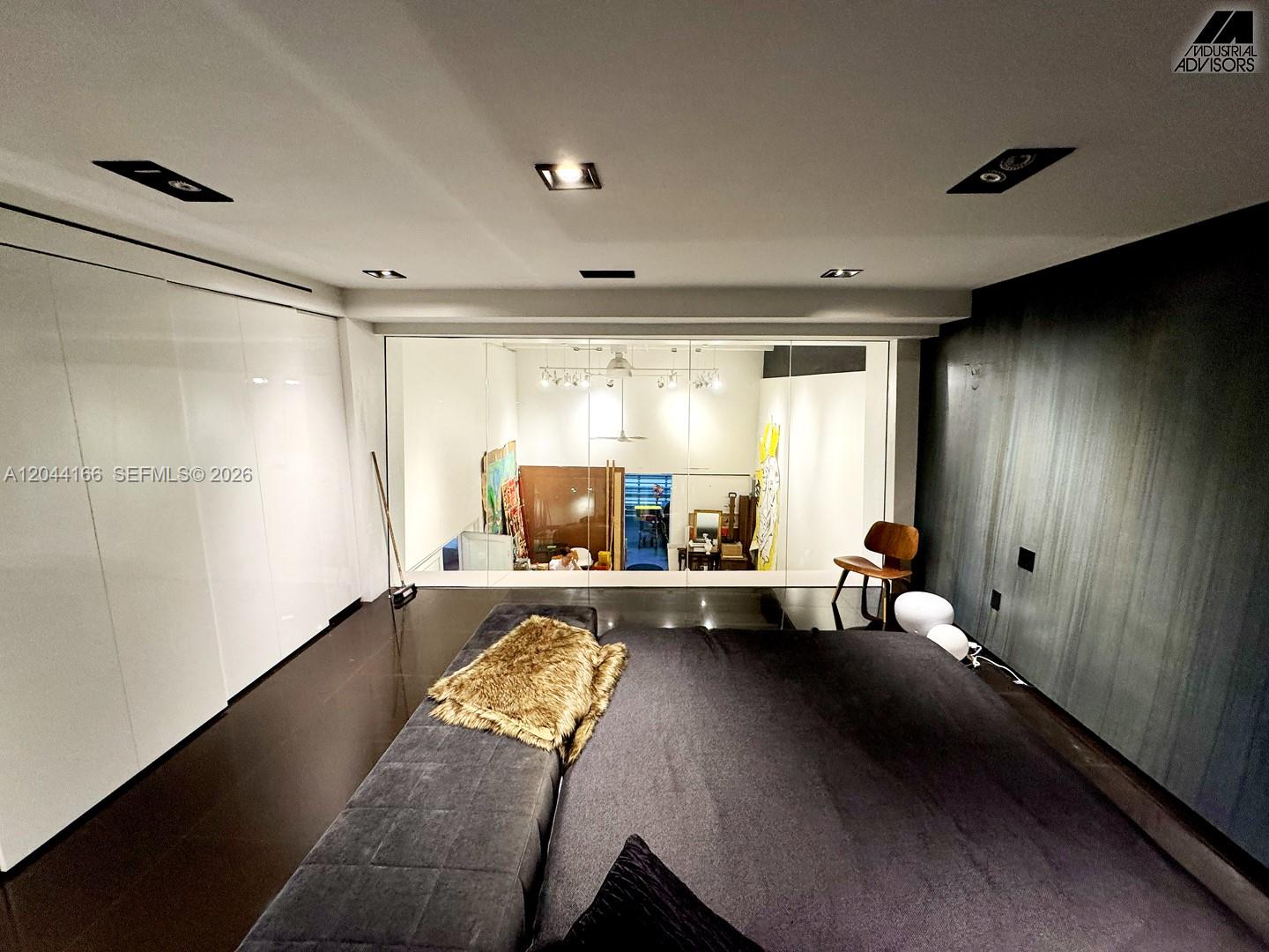 A bedroom with dark flooring, a large bed, and a glass wall overlooking another space — 2310 W 79th St, Hialeah FL 33016, HIALEAH, FL