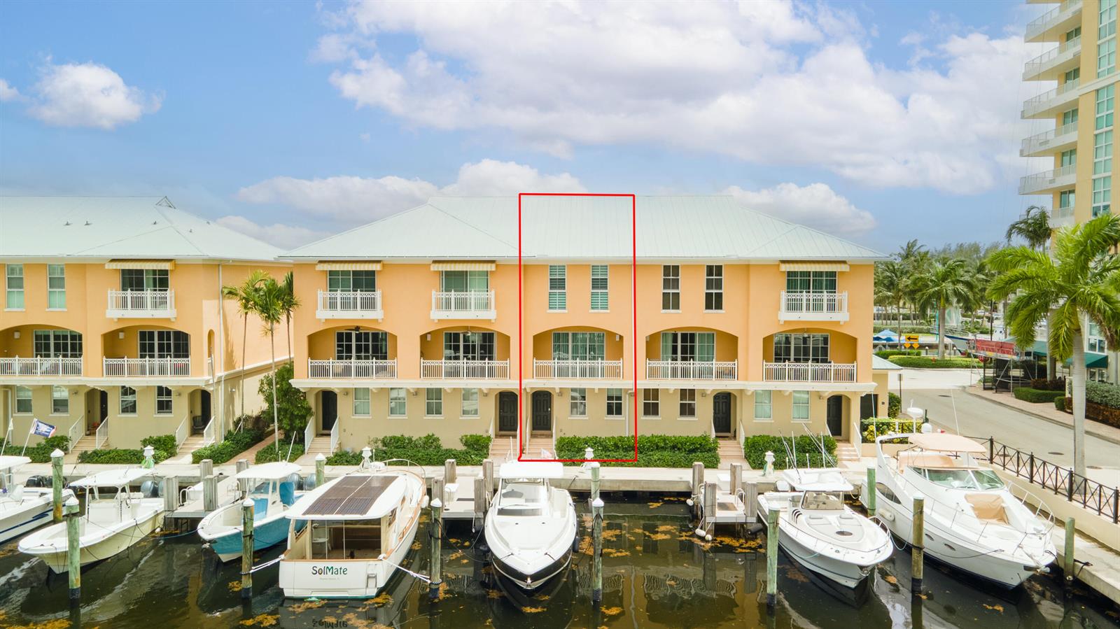 An exterior view of a multi-story, peach-colored waterfront townhouse with a boat docked in front — 643 Casa Loma Boulevard, Boynton Beach FL 33435, BOYNTON BEACH, FL