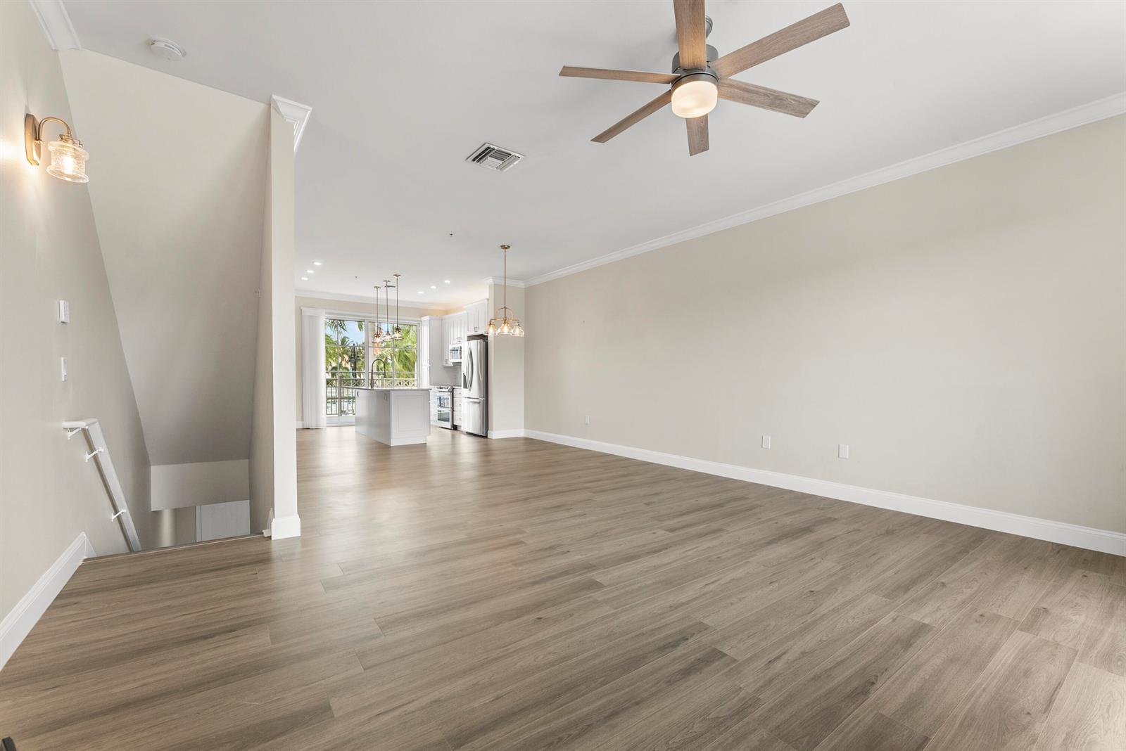An open-concept living area features light wood-look flooring, a ceiling fan, and a kitchen — 643 Casa Loma Boulevard, Boynton Beach FL 33435, BOYNTON BEACH, FL