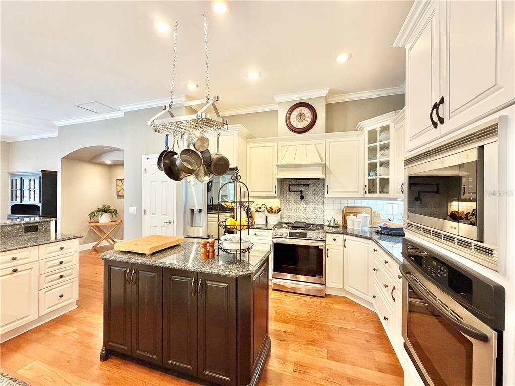 A kitchen features a dark wood island, white cabinetry, stainless steel appliances, and hardwood floors — 8613 SW 39TH LANE, GAINESVILLE, FL