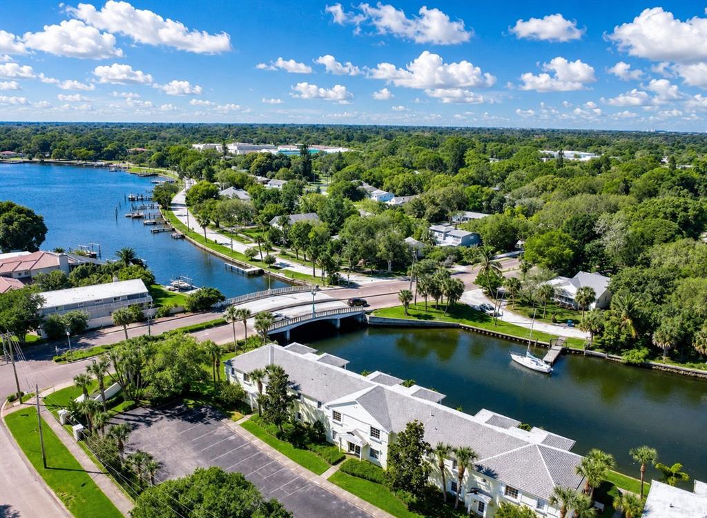 An aerial view shows a bridge crossing a canal near waterfront residential buildings and trees — 3889 POMPANO DRIVE SE UNIT C, ST PETERSBURG, FL