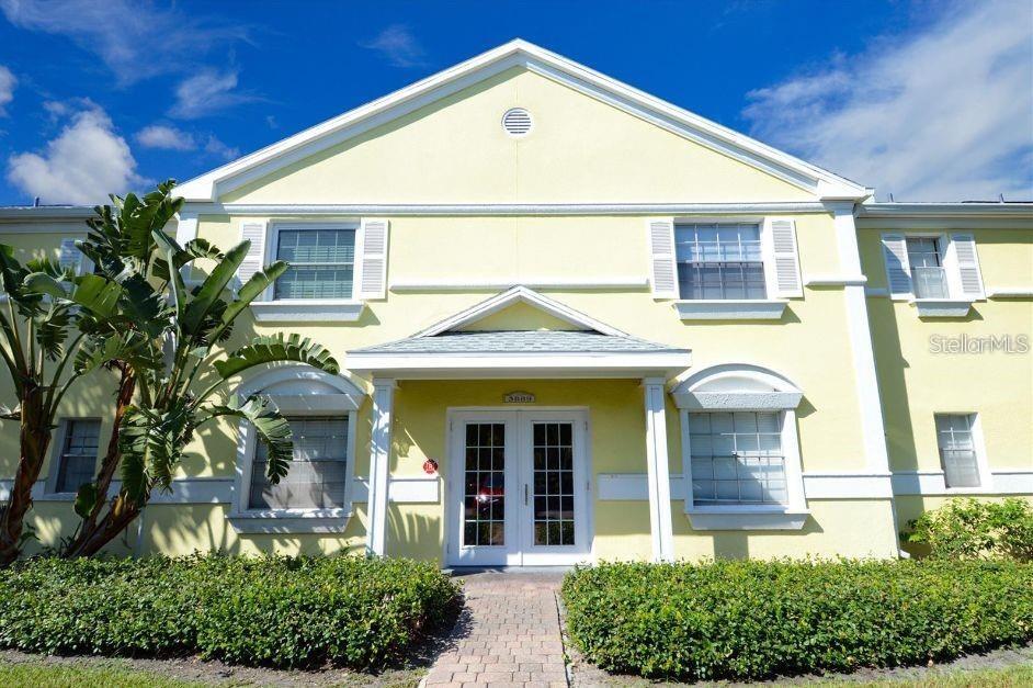A two-story yellow building features a central entrance with double glass doors and landscaping — 3889 POMPANO DRIVE SE UNIT C, ST PETERSBURG, FL