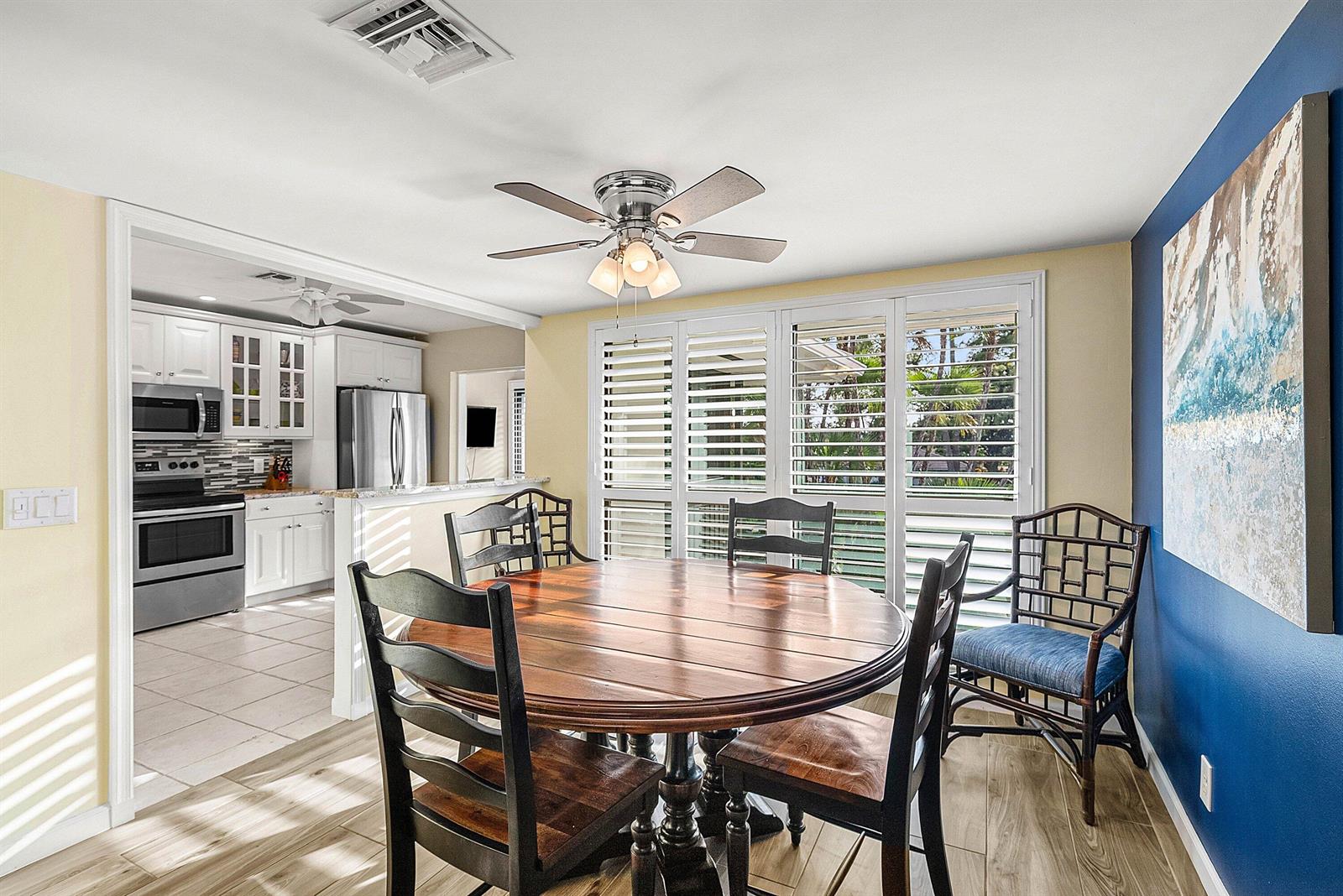 A dining room with a round wooden table, chairs, and a view into the kitchen — 11272 Quail Covey Road, Boynton Beach FL 33436, BOYNTON BEACH, FL