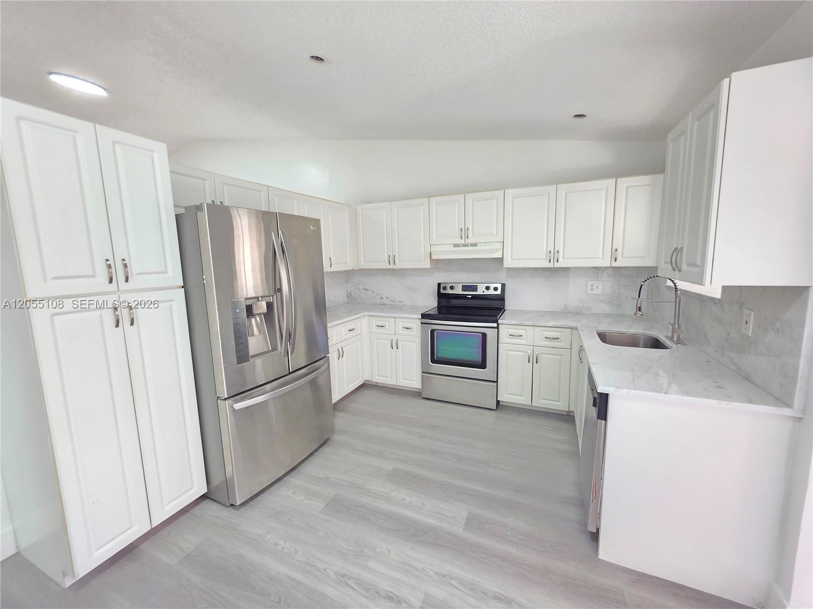 A kitchen features white cabinets, stainless steel appliances, and marble-look countertops over gray flooring — 5307 NW 93rd Ave # 0, Sunrise FL 33351, SUNRISE, FL
