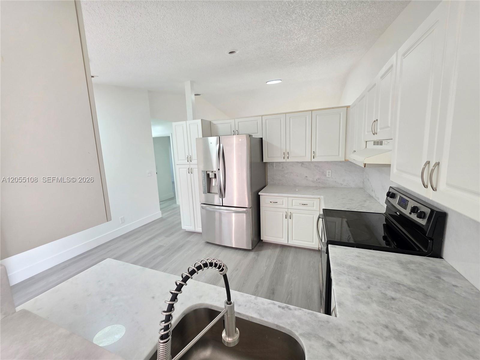 A kitchen features white cabinets, stainless steel appliances, and gray marble-patterned countertops — 5307 NW 93rd Ave # 0, Sunrise FL 33351, SUNRISE, FL