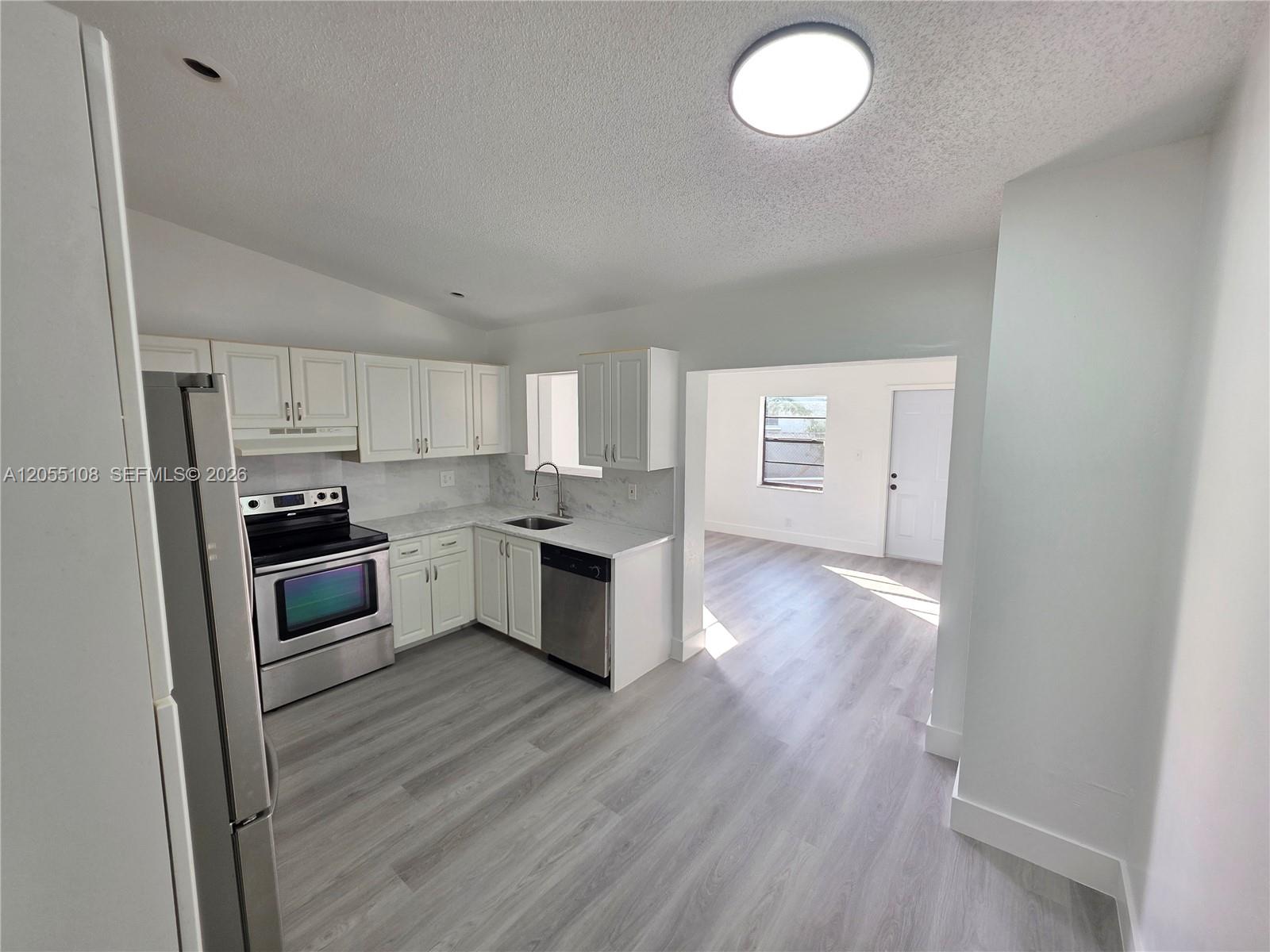 A kitchen with white cabinets, stainless steel appliances, and light wood-look flooring — 5307 NW 93rd Ave # 0, Sunrise FL 33351, SUNRISE, FL