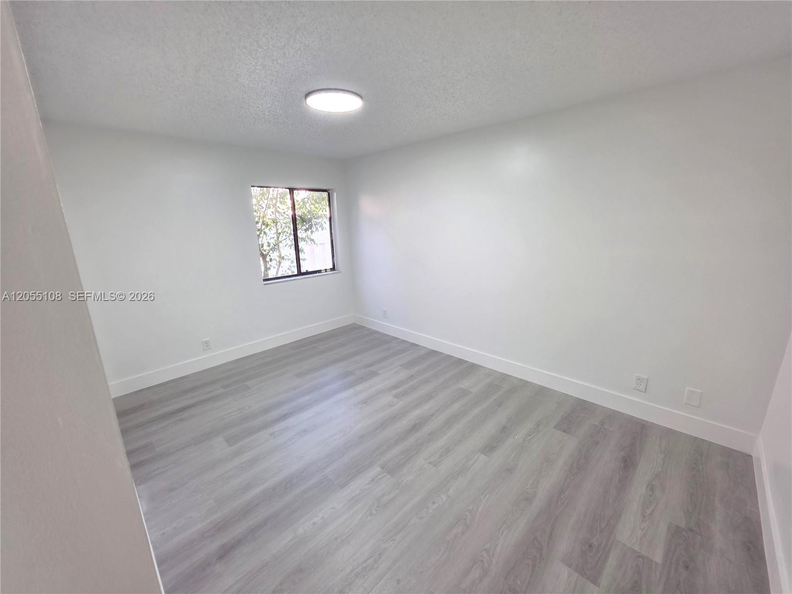 An empty bedroom features white walls, gray wood-look flooring, and a single window — 5307 NW 93rd Ave # 0, Sunrise FL 33351, SUNRISE, FL