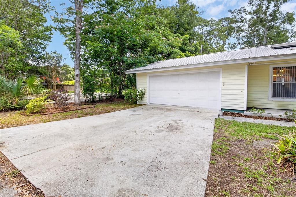A concrete driveway leads to a white garage door on a light-colored house — 1822 SW 42ND AVENUE, GAINESVILLE, FL