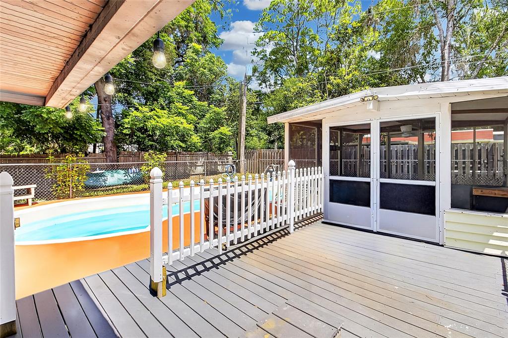 A wooden deck features a white picket fence overlooking a swimming pool and screened porch — 1822 SW 42ND AVENUE, GAINESVILLE, FL