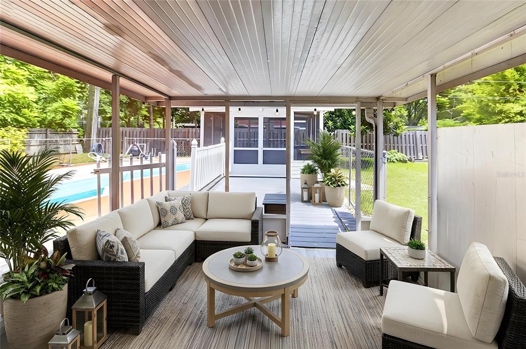 A screened-in patio features wicker furniture, a round coffee table, and a view of a pool — 1822 SW 42ND AVENUE, GAINESVILLE, FL