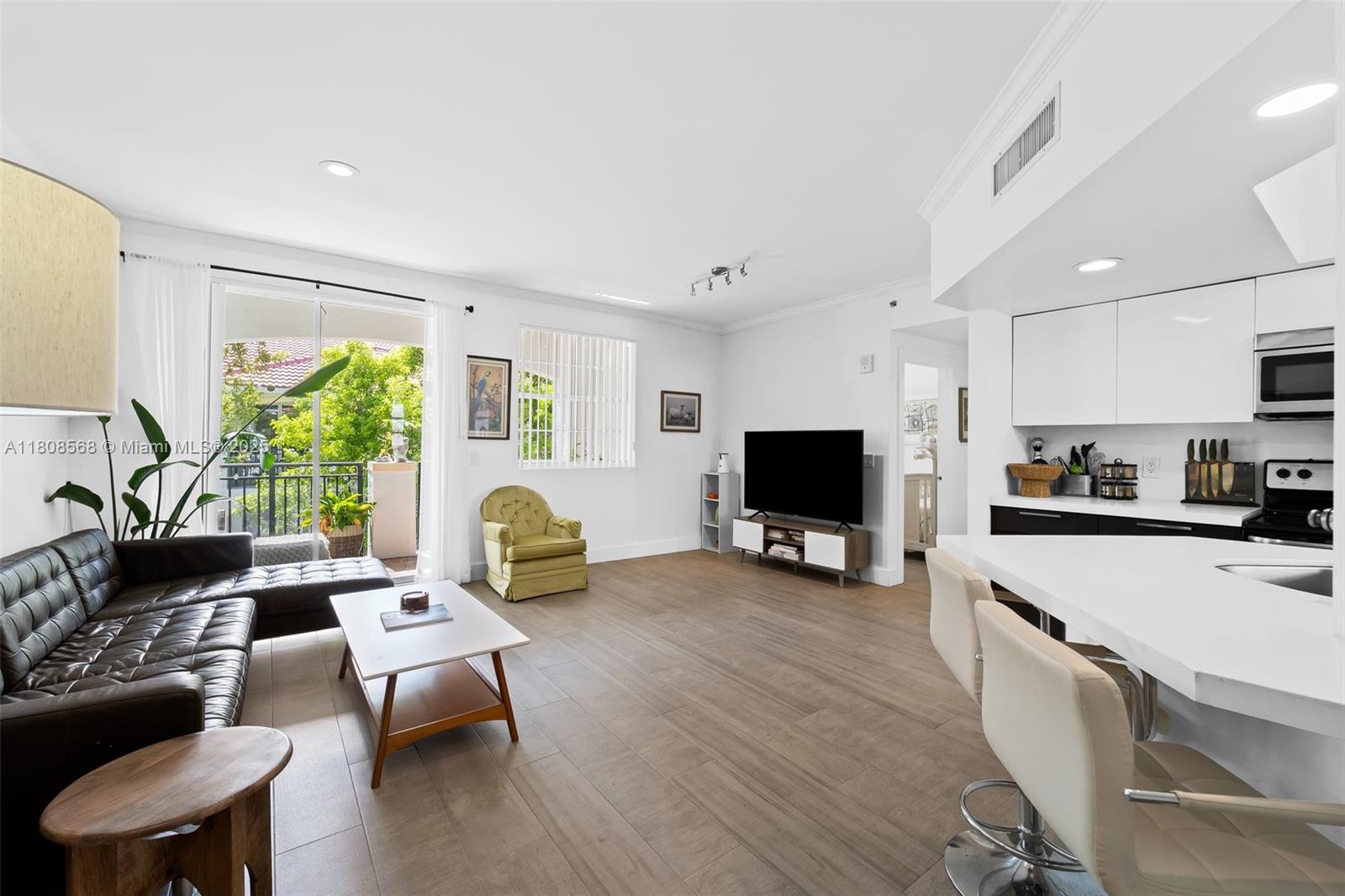 A living room with wood-look tile floors connects to a kitchen and a balcony — 3245 NE 184th St # 13402, Aventura FL 33160, AVENTURA, FL