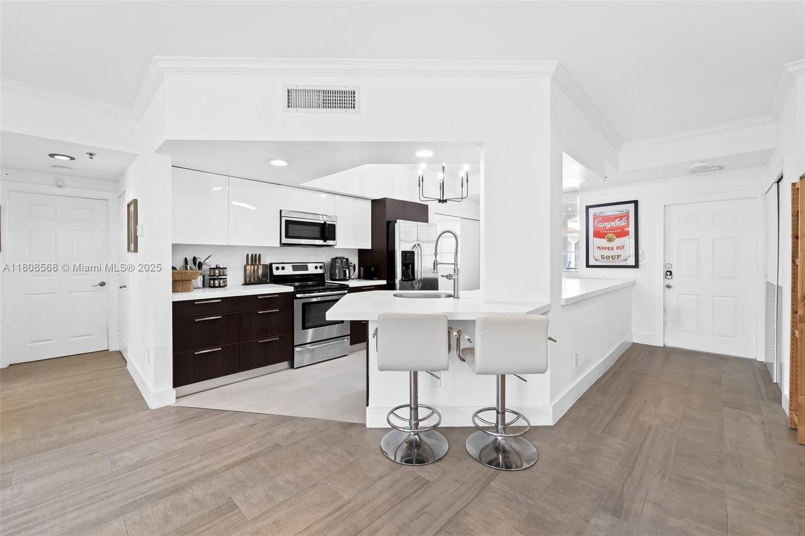 A modern kitchen features dark lower cabinets, white upper cabinets, and a breakfast bar with stools — 3245 NE 184th St # 13402, Aventura FL 33160, AVENTURA, FL