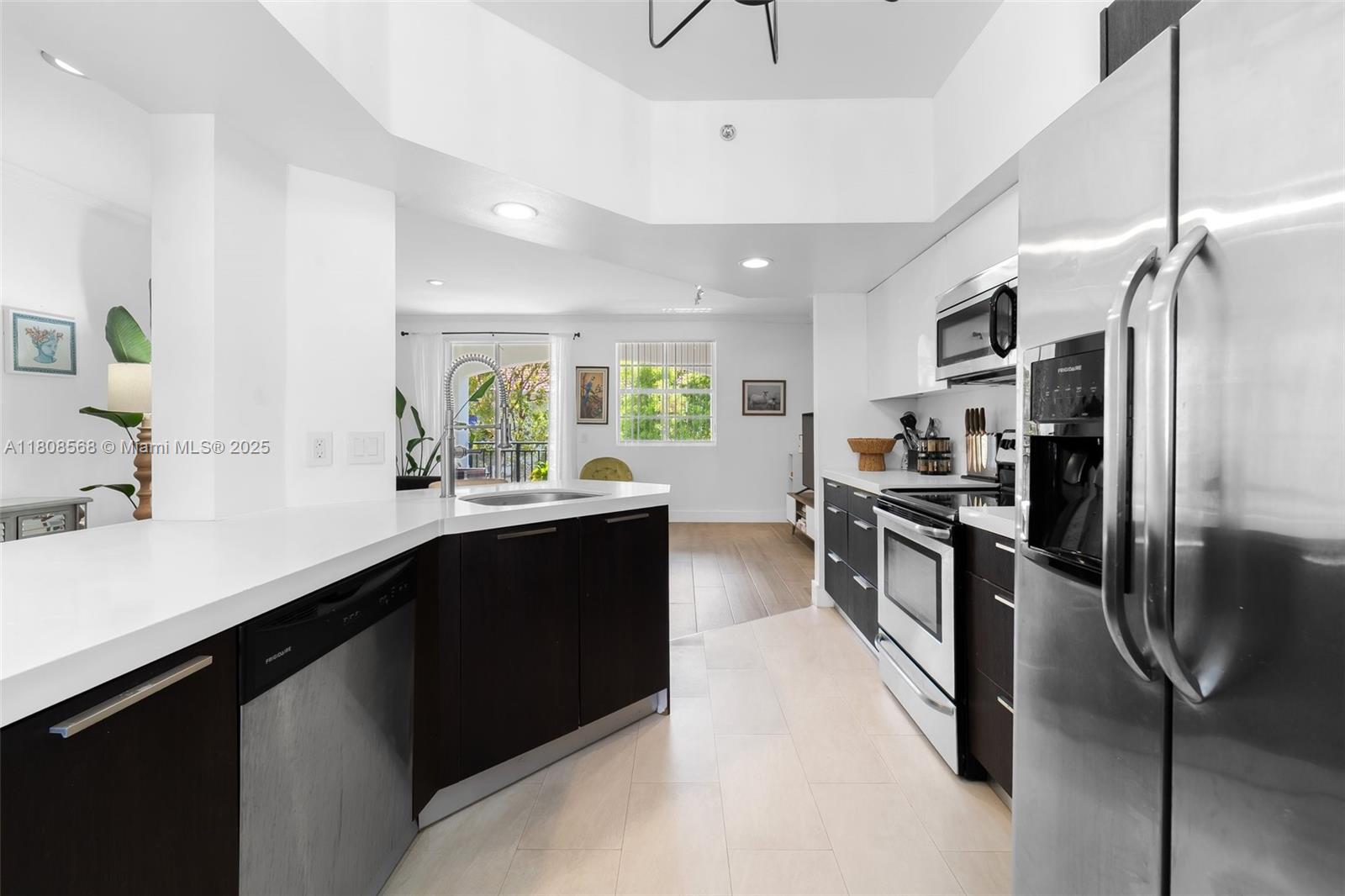A modern kitchen features dark cabinetry, white countertops, stainless steel appliances, and light tile flooring — 3245 NE 184th St # 13402, Aventura FL 33160, AVENTURA, FL