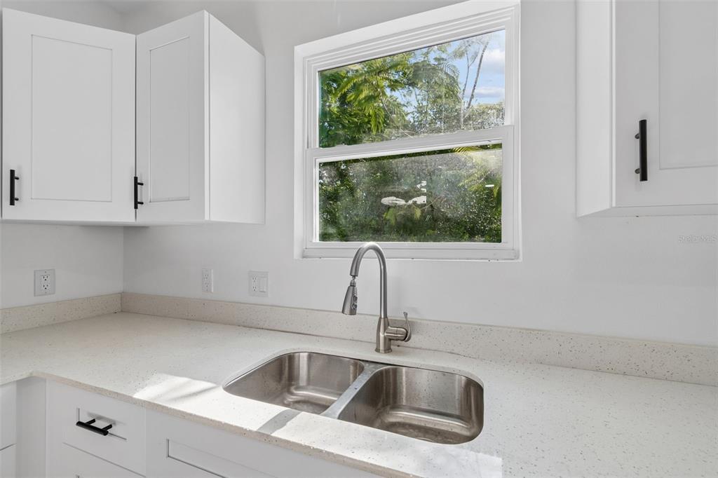 A kitchen sink with a stainless steel faucet sits below a window in a white kitchen — 2005 AVA CIRCLE, BARTOW, FL