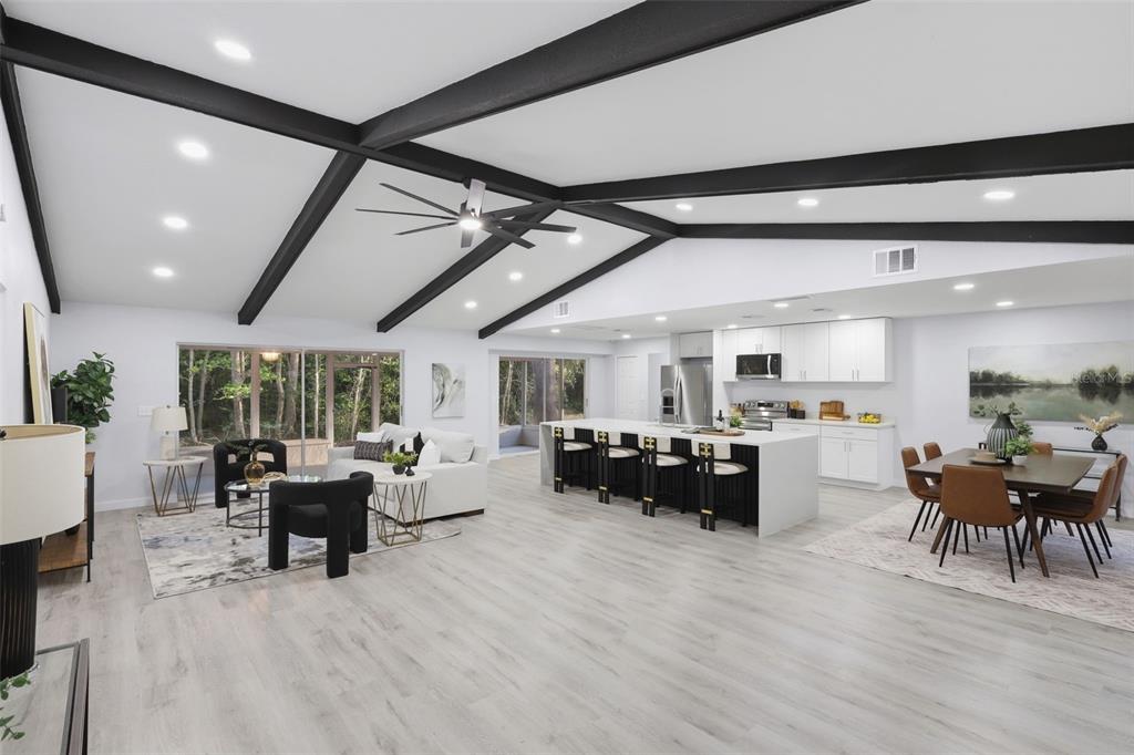 An open-concept living, kitchen, and dining area features vaulted ceilings with exposed black beams — 300 E SWEETWATER CREEK DRIVE, LONGWOOD, FL