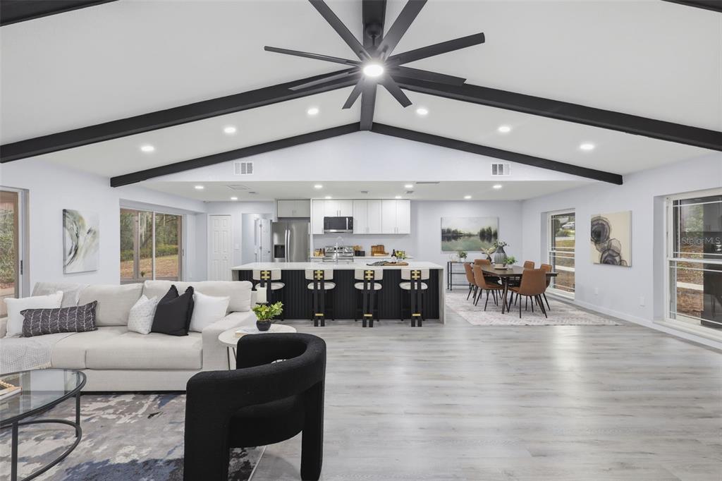 An open-concept living and dining area features a vaulted ceiling with exposed black beams — 300 E SWEETWATER CREEK DRIVE, LONGWOOD, FL