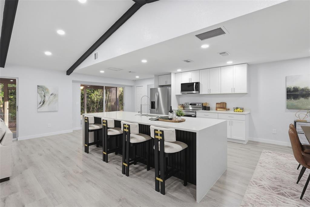A modern kitchen features a large white island with bar seating and white cabinetry — 300 E SWEETWATER CREEK DRIVE, LONGWOOD, FL