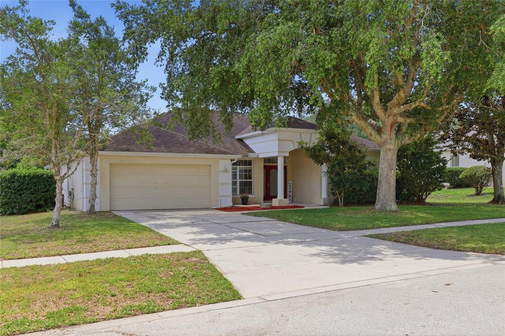 A single-story house with a beige exterior, a two-car garage, and a red front door — 610 GAELIC COURT, APOPKA, FL