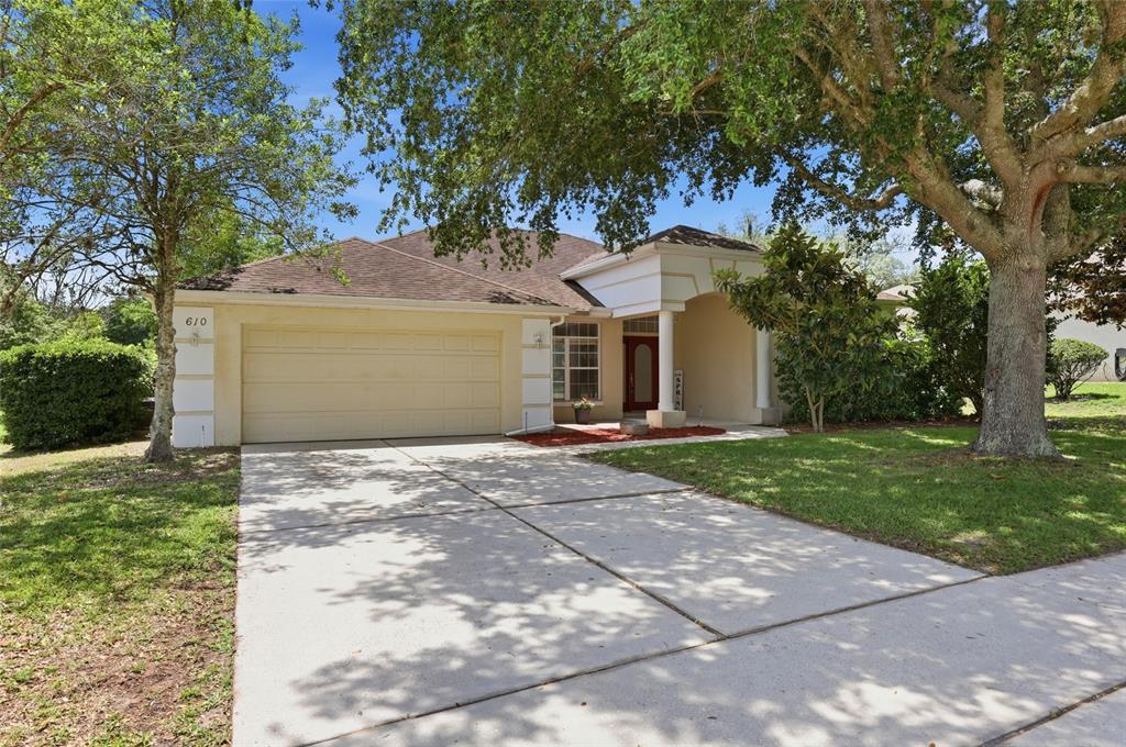 A single-story house with a beige stucco exterior, a two-car garage, and a covered entryway — 610 GAELIC COURT, APOPKA, FL