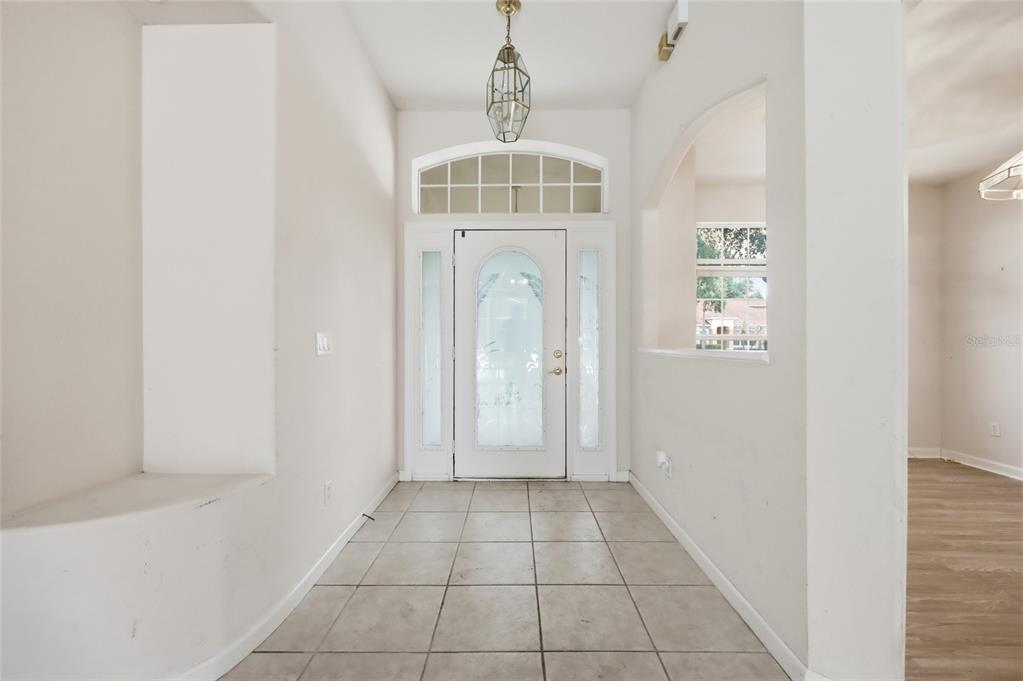 An entryway features tiled flooring, a white front door with glass inserts, and a pendant light — 610 GAELIC COURT, APOPKA, FL