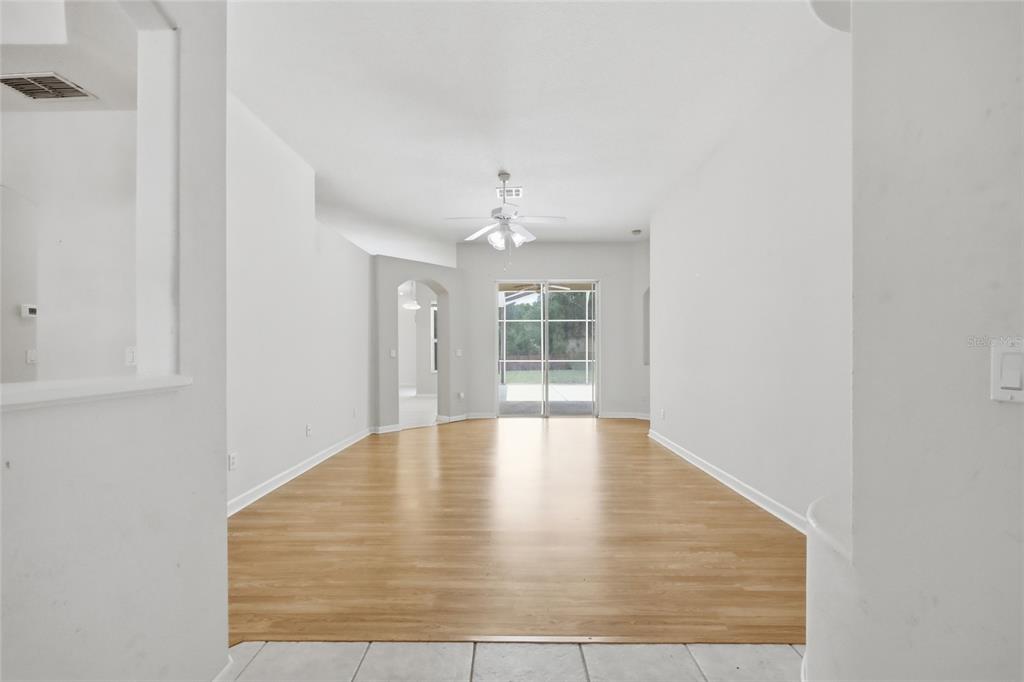 An empty living room with light wood flooring, white walls, and a sliding glass door — 610 GAELIC COURT, APOPKA, FL