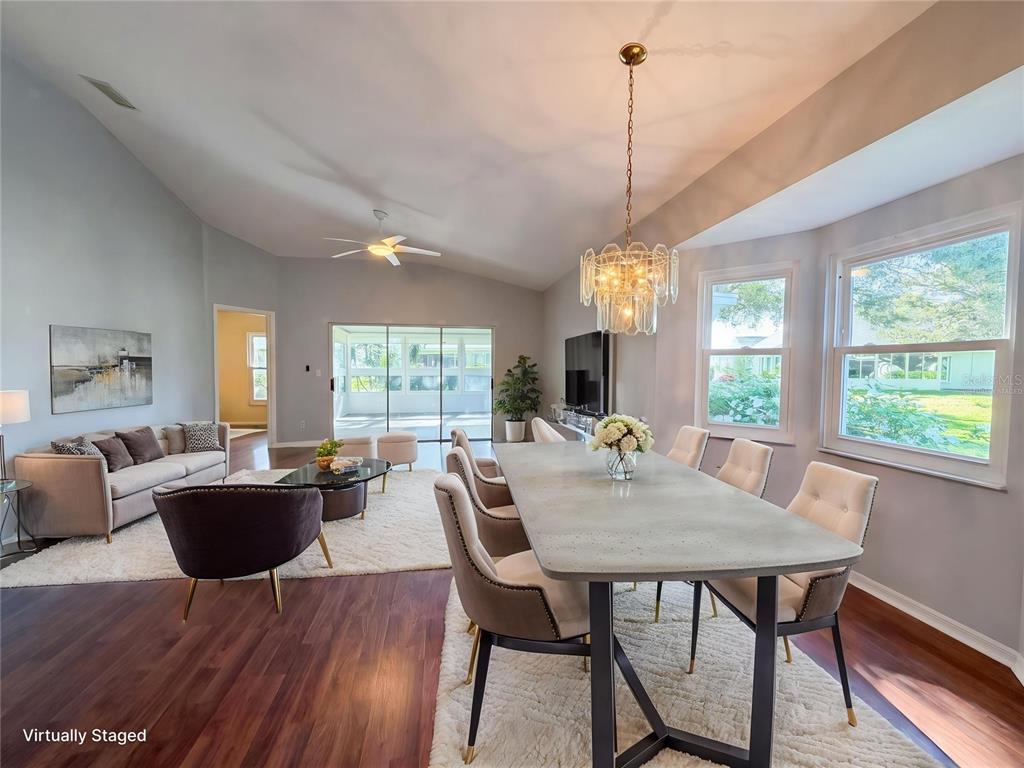 A living and dining area features vaulted ceilings, wood flooring, and a crystal chandelier — 2320 MARKSMEN COURT UNIT N/A, SUN CITY CENTER, FL