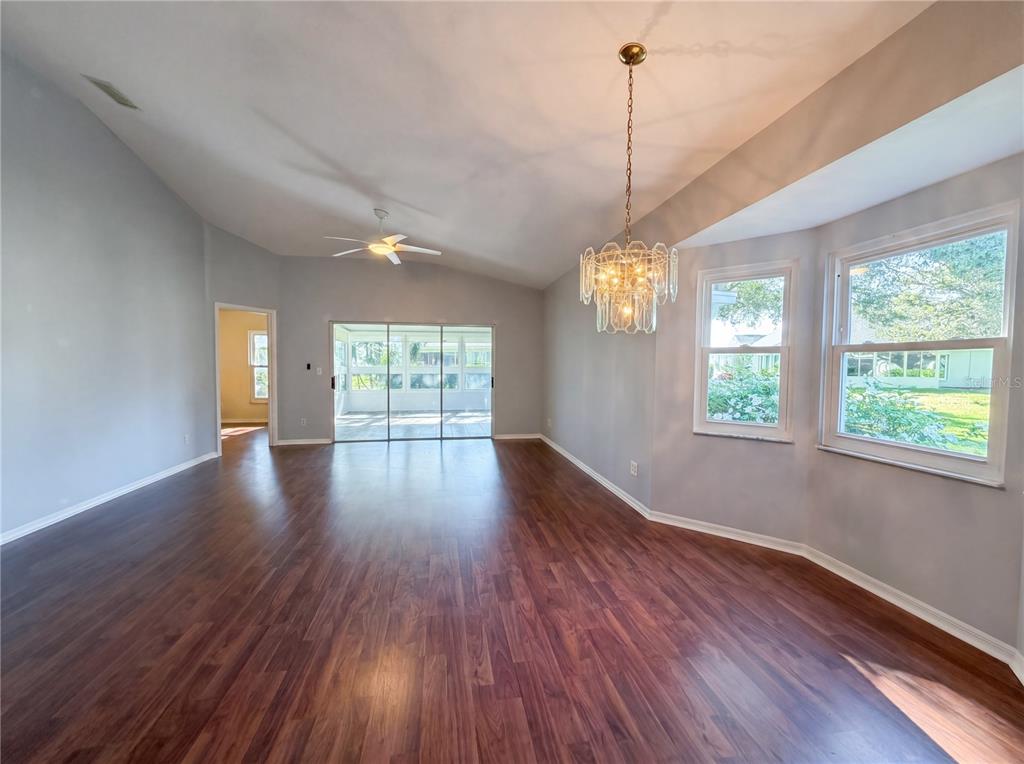 A spacious room features light gray walls, dark wood-look flooring, a chandelier, and sliding doors — 2320 MARKSMEN COURT UNIT N/A, SUN CITY CENTER, FL