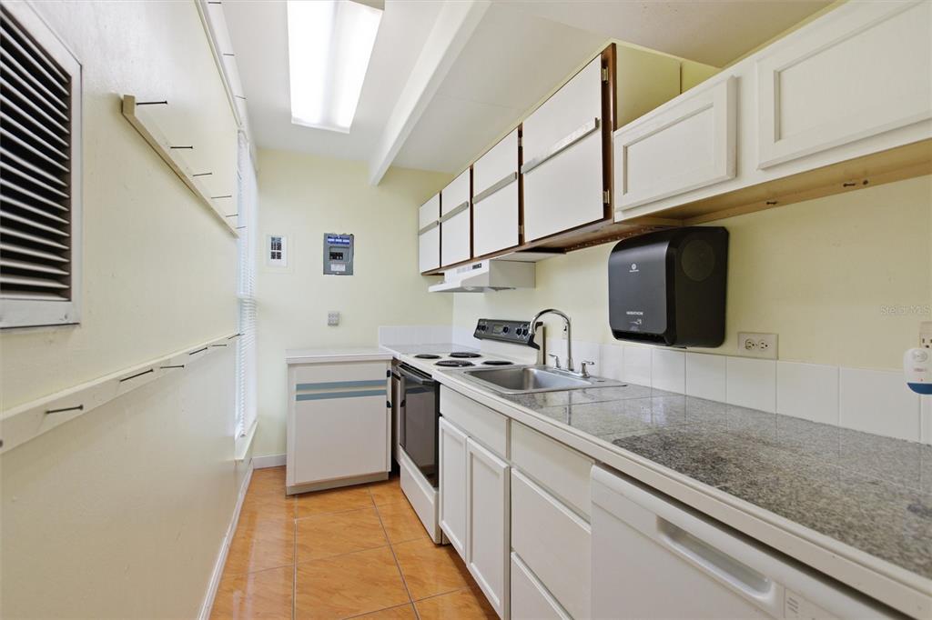 A galley kitchen features white cabinets, granite countertops, tile flooring, and a black paper towel dispenser — 2637 CLUB CIRCLE, LAKE WALES, FL