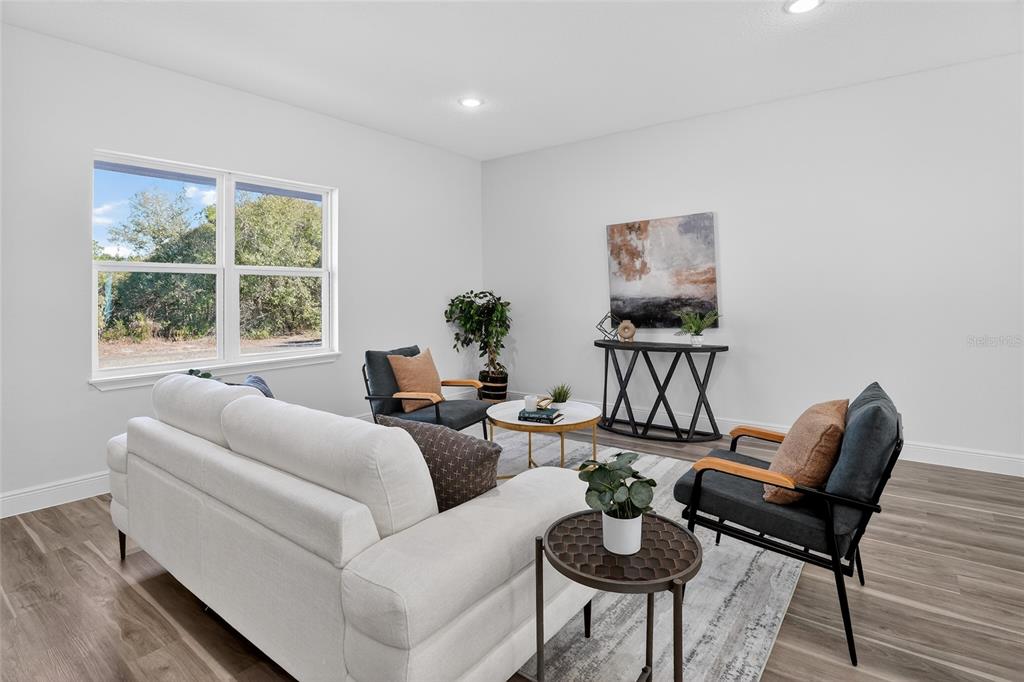 A living room features a white sofa, two armchairs, a coffee table, and wood-look flooring — 1957 W OLIVER DRIVE, CITRUS SPRINGS, FL