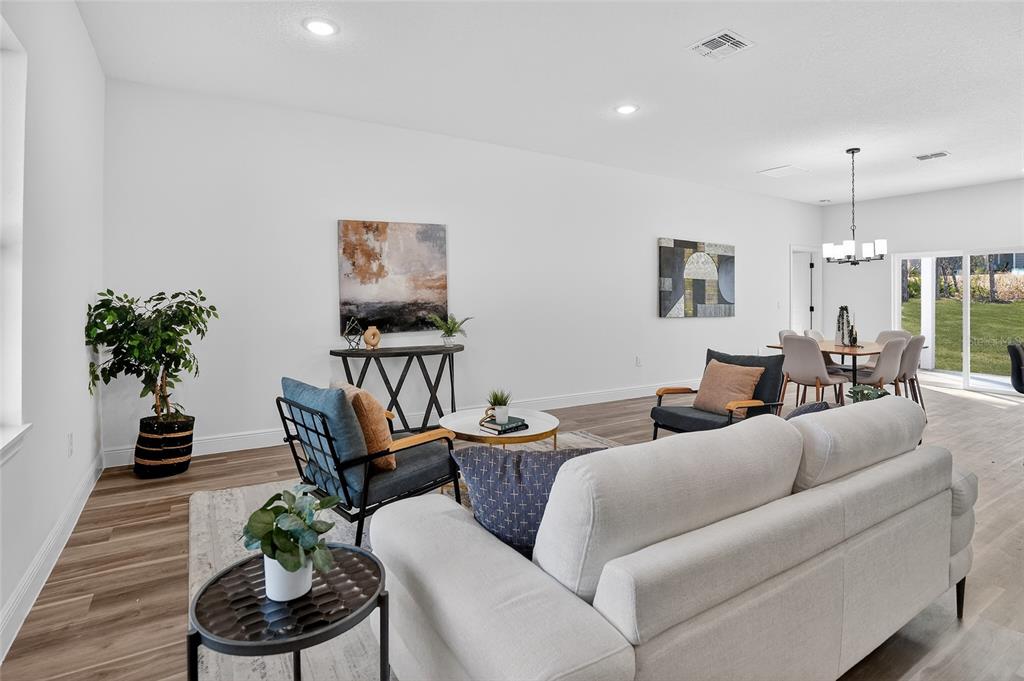 A bright, open-concept living and dining area features light wood flooring and modern furniture — 1957 W OLIVER DRIVE, CITRUS SPRINGS, FL