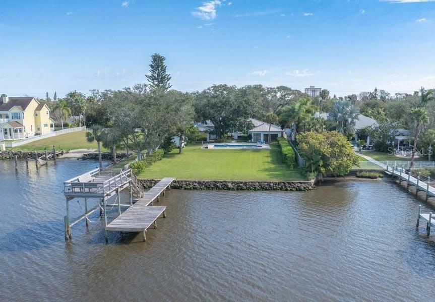 An aerial view shows a waterfront property with a large lawn, pool, and wooden dock — 1596 JOHN ANDERSON DRIVE, ORMOND BEACH, FL