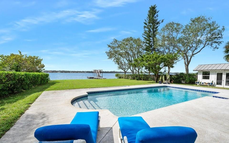 A swimming pool sits on a patio overlooking a large body of water — 1596 JOHN ANDERSON DRIVE, ORMOND BEACH, FL