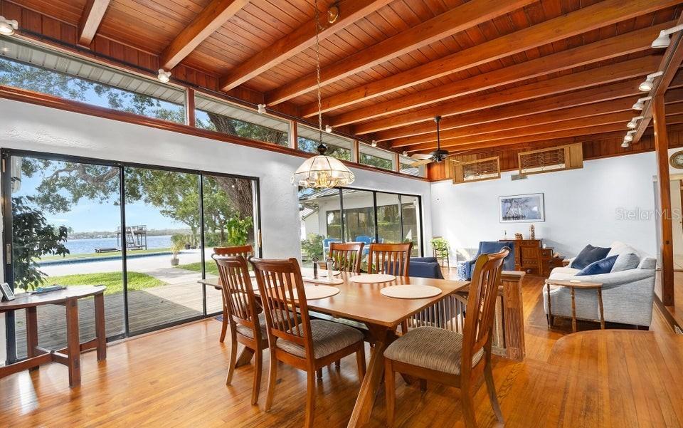 A dining area with wood-beamed ceilings and large sliding glass doors overlooking a waterfront yard — 1596 JOHN ANDERSON DRIVE, ORMOND BEACH, FL